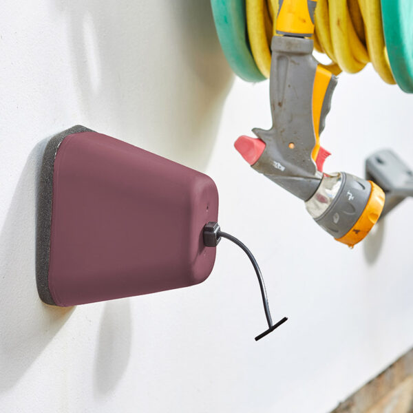 A burgundy Winter Protection Anti-Freeze Tap Cover mounted on a white wall.
